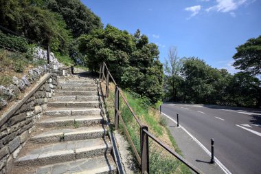 Güneşli bir günde etrafı ormanla çevrili bir uçurumun kenarındaki virajın yanındaki merdivende.