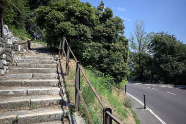 Güneşli bir günde etrafı ormanla çevrili bir uçurumun kenarındaki virajın yanındaki merdivende.