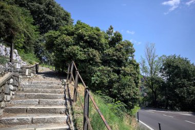 Güneşli bir günde etrafı ormanla çevrili bir uçurumun kenarındaki virajın yanındaki merdivende.