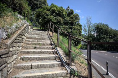 Güneşli bir günde etrafı ormanla çevrili bir uçurumun kenarındaki virajın yanındaki merdivende.