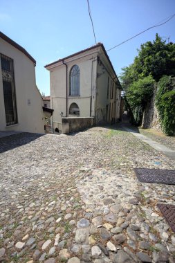 Fork between two cobbled street on a hill divided by the corner of a building on a sunny day