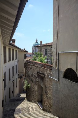 Güneşli bir günde arka planda bir kilisenin kubbesi olan bir binayla taş duvar arasında bir merdivenden yapılmış.