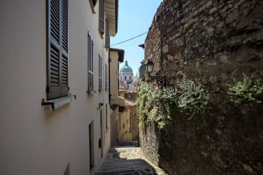 Güneşli bir günde arka planda bir kilisenin kubbesi olan bir binayla taş duvar arasında bir merdivenden yapılmış.