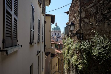 Güneşli bir günde arka planda bir kilisenin kubbesi olan bir binayla taş duvar arasında bir merdivenden yapılmış.