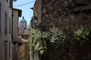 Güneşli bir günde arka planda bir kilisenin kubbesi olan bir binayla taş duvar arasında bir merdivenden yapılmış.