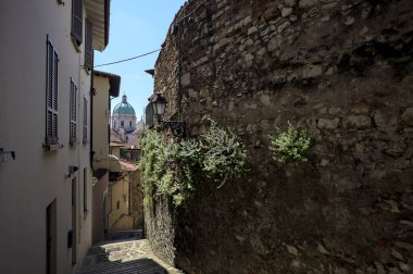 Güneşli bir günde arka planda bir kilisenin kubbesi olan bir binayla taş duvar arasında bir merdivenden yapılmış.