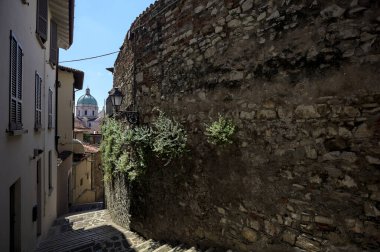 Güneşli bir günde arka planda bir kilisenin kubbesi olan bir binayla taş duvar arasında bir merdivenden yapılmış.