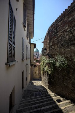 Güneşli bir günde arka planda bir kilisenin kubbesi olan bir binayla taş duvar arasında bir merdivenden yapılmış.