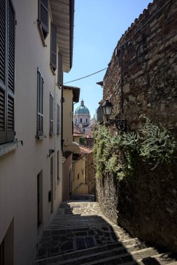 Güneşli bir günde arka planda bir kilisenin kubbesi olan bir binayla taş duvar arasında bir merdivenden yapılmış.