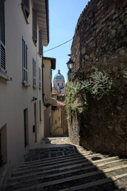 Güneşli bir günde arka planda bir kilisenin kubbesi olan bir binayla taş duvar arasında bir merdivenden yapılmış.