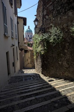 Güneşli bir günde arka planda bir kilisenin kubbesi olan bir binayla taş duvar arasında bir merdivenden yapılmış.