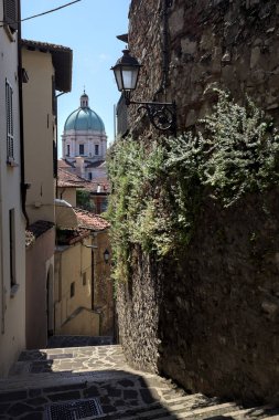 Güneşli bir günde arka planda bir kilisenin kubbesi olan bir binayla taş duvar arasında bir merdivenden yapılmış.