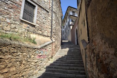 Güneşli bir günde, üzerinde sokak lambaları olan bir bina ile taştan bir cephenin arasındaki merdivenlere tırmanmak.