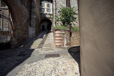 Merdivenler bir uçuruma tırmanıyor, bir binanın altındaki kemere, bir sokak aşağıdan görünüyor.