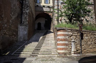 Merdivenler bir uçuruma tırmanıyor, bir binanın altındaki kemere, bir sokak aşağıdan görünüyor.