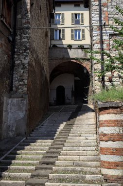 Merdivenler bir uçuruma tırmanıyor, bir binanın altındaki kemere, bir sokak aşağıdan görünüyor.