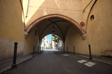 Bir İtalyan kasabasında sokak üstü kapalı bir kemer geçidinden geçiyor.