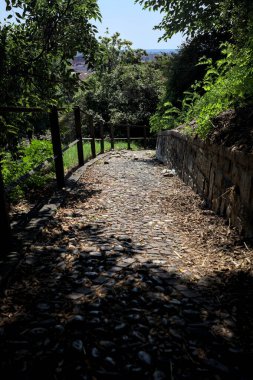 Güneşli bir günde, bir uçurumun kenarında çakıllı bir patika.