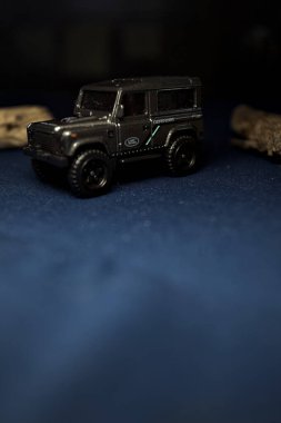 Mantova, Italy - 10TH AUGUST 2025 - Hot Wheels replica of a Land Rover Defender 90 pretending to cross a creek with trunks in it