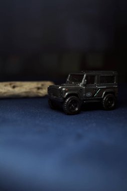 Mantova, Italy - 10TH AUGUST 2025 - Hot Wheels replica of a Land Rover Defender 90 pretending to cross a creek with trunks in it