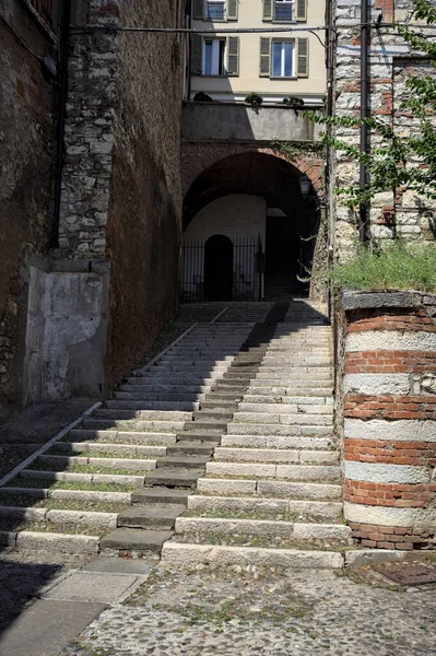 Merdivenler bir uçuruma tırmanıyor, bir binanın altındaki kemere, bir sokak aşağıdan görünüyor.