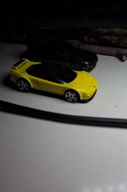 Mantova, Italy - 10TH AUGUST 2025 - Hot Wheels replicas of a black Nissan Skyline GT-R R32 and a yellow 1990 Acura NSX pretending to drift during a race on a mountain pass