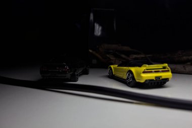 Mantova, Italy - 10TH AUGUST 2025 - Hot Wheels replicas of a black Nissan Skyline GT-R R32 and a yellow 1990 Acura NSX pretending to drift during a race on a mountain pass