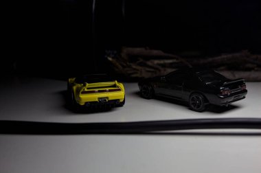Mantova, Italy - 10TH AUGUST 2025 - Hot Wheels replicas of a black Nissan Skyline GT-R R32 and a yellow 1990 Acura NSX pretending to drift during a race on a mountain pass