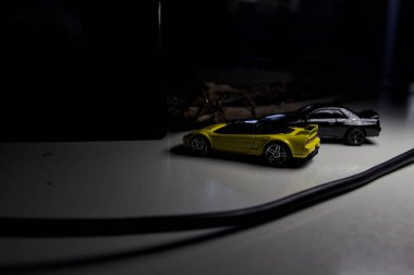 Mantova, Italy - 10TH AUGUST 2025 - Hot Wheels replicas of a black Nissan Skyline GT-R R32 and a yellow 1990 Acura NSX pretending to drift during a race on a mountain pass