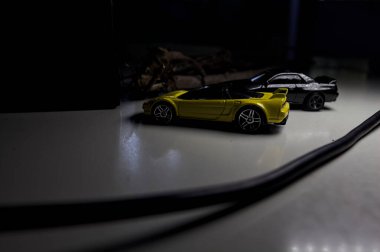 Mantova, Italy - 10TH AUGUST 2025 - Hot Wheels replicas of a black Nissan Skyline GT-R R32 and a yellow 1990 Acura NSX pretending to drift during a race on a mountain pass