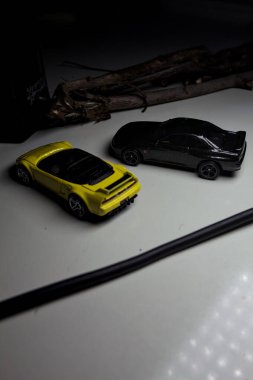 Mantova, Italy - 10TH AUGUST 2025 - Hot Wheels replicas of a black Nissan Skyline GT-R R32 and a yellow 1990 Acura NSX pretending to drift during a race on a mountain pass