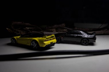 Mantova, Italy - 10TH AUGUST 2025 - Hot Wheels replicas of a black Nissan Skyline GT-R R32 and a yellow 1990 Acura NSX pretending to drift during a race on a mountain pass