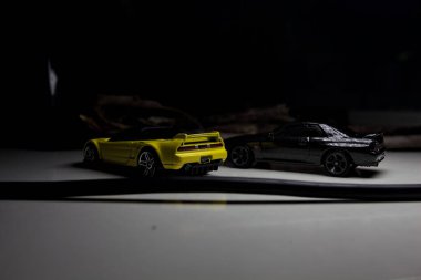 Mantova, Italy - 10TH AUGUST 2025 - Hot Wheels replicas of a black Nissan Skyline GT-R R32 and a yellow 1990 Acura NSX pretending to drift during a race on a mountain pass