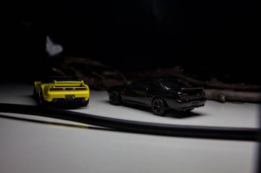 Mantova, Italy - 10TH AUGUST 2025 - Hot Wheels replicas of a black Nissan Skyline GT-R R32 and a yellow 1990 Acura NSX pretending to drift during a race on a mountain pass