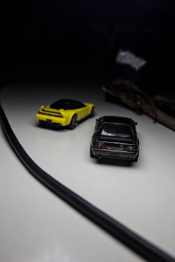 Mantova, Italy - 10TH AUGUST 2025 - Hot Wheels replicas of a black Nissan Skyline GT-R R32 and a yellow 1990 Acura NSX pretending to drift during a race on a mountain pass