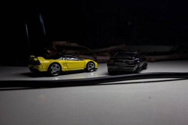 Mantova, Italy - 10TH AUGUST 2025 - Hot Wheels replicas of a black Nissan Skyline GT-R R32 and a yellow 1990 Acura NSX pretending to drift during a race on a mountain pass