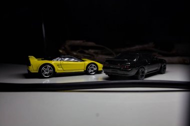 Mantova, Italy - 10TH AUGUST 2025 - Hot Wheels replicas of a black Nissan Skyline GT-R R32 and a yellow 1990 Acura NSX pretending to drift during a race on a mountain pass