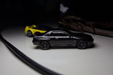 Mantova, Italy - 10TH AUGUST 2025 - Hot Wheels replicas of a black Nissan Skyline GT-R R32 and a yellow 1990 Acura NSX pretending to drift during a race on a mountain pass