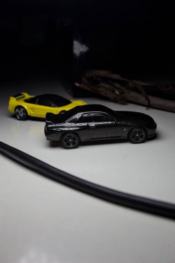 Mantova, Italy - 10TH AUGUST 2025 - Hot Wheels replicas of a black Nissan Skyline GT-R R32 and a yellow 1990 Acura NSX pretending to drift during a race on a mountain pass