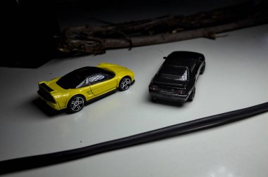 Mantova, Italy - 10TH AUGUST 2025 - Hot Wheels replicas of a black Nissan Skyline GT-R R32 and a yellow 1990 Acura NSX pretending to drift during a race on a mountain pass