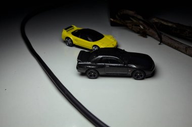 Mantova, Italy - 10TH AUGUST 2025 - Hot Wheels replicas of a black Nissan Skyline GT-R R32 and a yellow 1990 Acura NSX pretending to drift during a race on a mountain pass