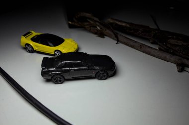 Mantova, Italy - 10TH AUGUST 2025 - Hot Wheels replicas of a black Nissan Skyline GT-R R32 and a yellow 1990 Acura NSX pretending to drift during a race on a mountain pass