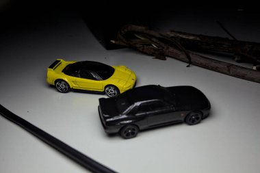 Mantova, Italy - 10TH AUGUST 2025 - Hot Wheels replicas of a black Nissan Skyline GT-R R32 and a yellow 1990 Acura NSX pretending to drift during a race on a mountain pass