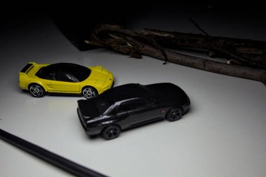 Mantova, Italy - 10TH AUGUST 2025 - Hot Wheels replicas of a black Nissan Skyline GT-R R32 and a yellow 1990 Acura NSX pretending to drift during a race on a mountain pass