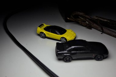 Mantova, Italy - 10TH AUGUST 2025 - Hot Wheels replicas of a black Nissan Skyline GT-R R32 and a yellow 1990 Acura NSX pretending to drift during a race on a mountain pass