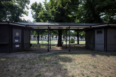 Closed kiosk in the shade under a few trees in a park on a sunny day