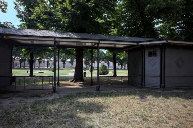 Closed kiosk in the shade under a few trees in a park on a sunny day