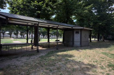 Closed kiosk in the shade under a few trees in a park on a sunny day