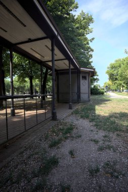 Closed kiosk in the shade under a few trees in a park on a sunny day