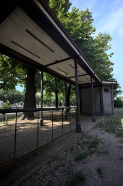 Closed kiosk in the shade under a few trees in a park on a sunny day